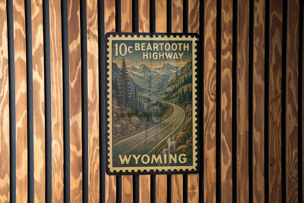 A vintage-style postage stamp depicting a scenic highway in Wyoming, mounted on a wooden wall.