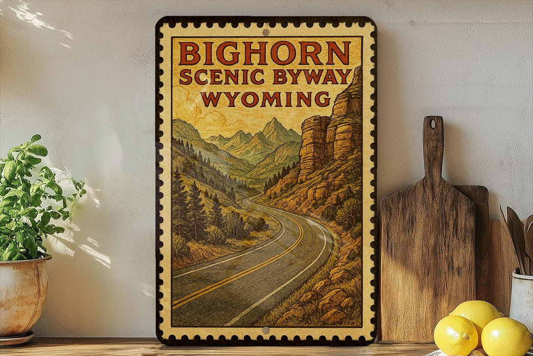 A framed vintage-style poster of the Big Horn Scenic Byway in Wyoming, featuring a winding road surrounded by mountains and pine trees.