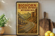 A framed vintage-style poster of the Big Horn Scenic Byway in Wyoming, featuring a winding road surrounded by mountains and pine trees.
