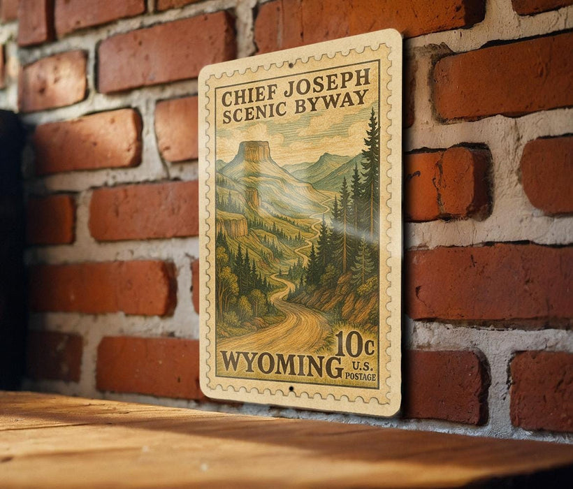A vintage-style postage stamp depicting a scenic landscape with mountains and a winding road, mounted on a brick wall.