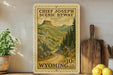 A framed postcard depicting the scenic beauty of Chief Joseph Scenic Byway in Wyoming, with a mountain landscape and winding road.