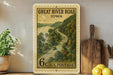 A framed postage stamp depicting a scenic road through Iowa, with a river and lush greenery in the background.