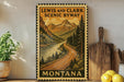 A framed vintage-style sign depicting a scenic mountain landscape with a winding road, surrounded by pine trees and mountains, with the text "LEWIS AND CLARK SCENIC BYWAY" and "MISSOURI" printed on it.