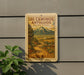 A vintage-style sign for the Los Caminos Antiguos scenic byway in Colorado, featuring a mountain landscape and a winding road.