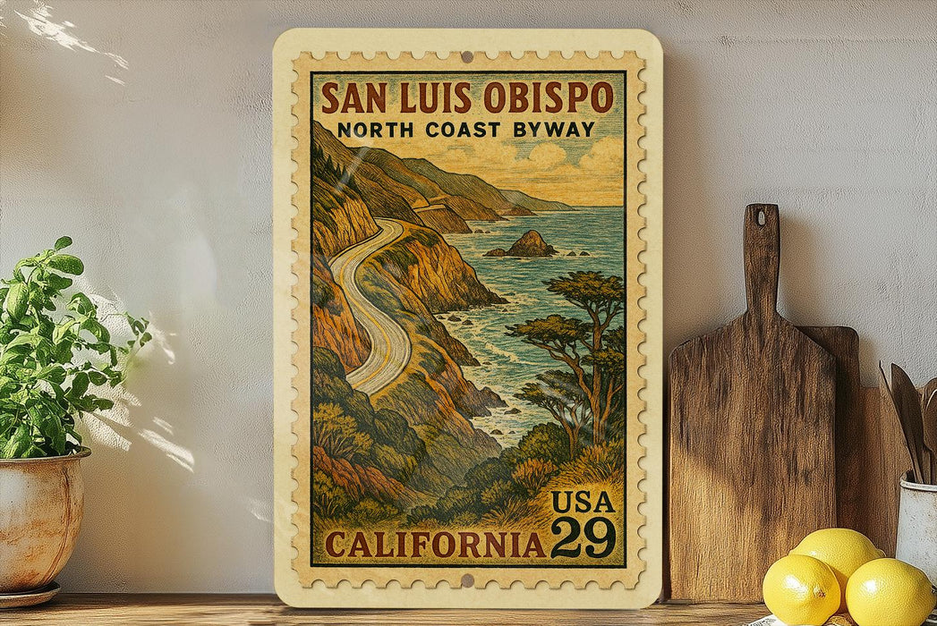 A framed vintage postage stamp depicting a scenic coastal road in California, with mountains, water, and trees in the background.