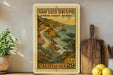 A framed vintage postage stamp depicting a scenic coastal road in California, with mountains, water, and trees in the background.
