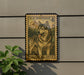 A U.S. postage stamp featuring a dog, likely an Alaskan Malamute, is mounted on a wall next to a plant.