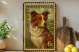 A vintage-style metal stamp depicting a Border Collie dog, with the text "BORDER COLLIE" and the denomination "6c". The stamp is placed on a shelf next to a wooden cutting board and a potted plant.