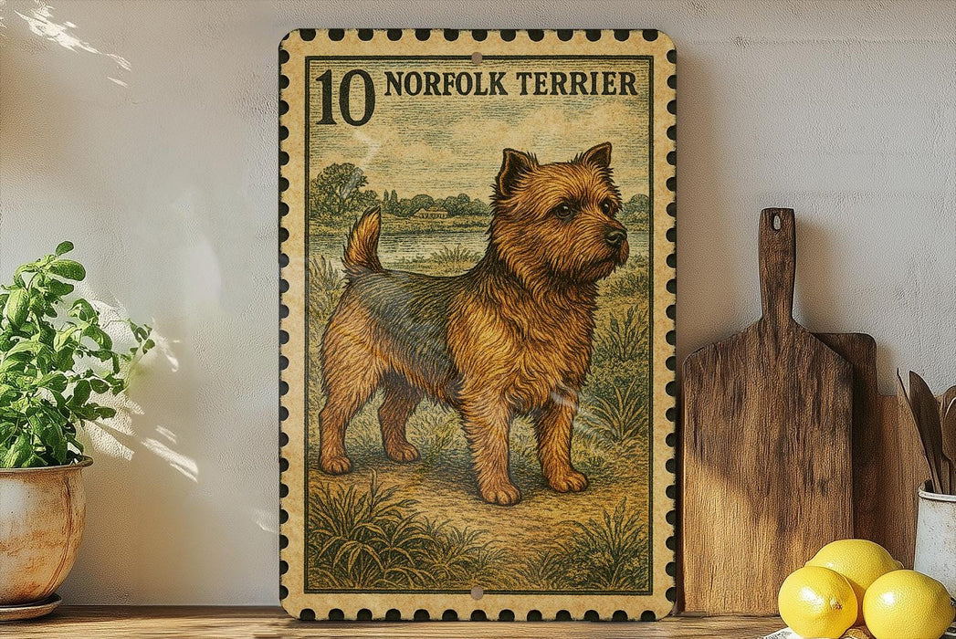 a framed illustration of a Norfolk Terrier dog, which is a type of terrier breed. The dog is depicted in a pastoral setting, surrounded by grass and trees. The frame has a decorative border and the text "10 NORFOLK TERRITOR" is visible, indicating the dog's breed.