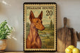 A framed illustration of a brown Egyptian Hound dog, with a vintage-style stamp design, is displayed on a shelf next to a wooden cutting board and some lemons.