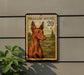 a brown dog, specifically a brown hound, depicted on a postage stamp-like frame.