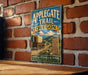 A vintage-style metal sign for the Applegate Trail in Oregon, featuring a wagon train and mountains in the background.