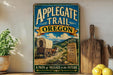 A vintage-style sign for the Applegate Trail in Oregon, featuring a wagon train on a dirt road with mountains in the background.