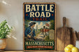 A vintage metal sign on a shelf, depicting a group of soldiers in historical uniforms and a British flag, with the text "BATTLE ROAD - TRAIL - MASSACHUSETTS - WALK WHERE HISTORY WAS MADE".