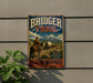 A vintage metal sign for the Bridger Trail in Wyoming, featuring a cowboy on a horse and a wagon, mounted on a wall.