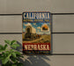 A vintage-style metal sign for the California National Historic Trail in Nebraska, featuring an image of a covered wagon and the text "Follow the Trail of History".