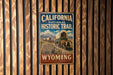 A vintage metal sign for the California National Historic Trail, featuring an illustration of a wagon train traveling through the state.