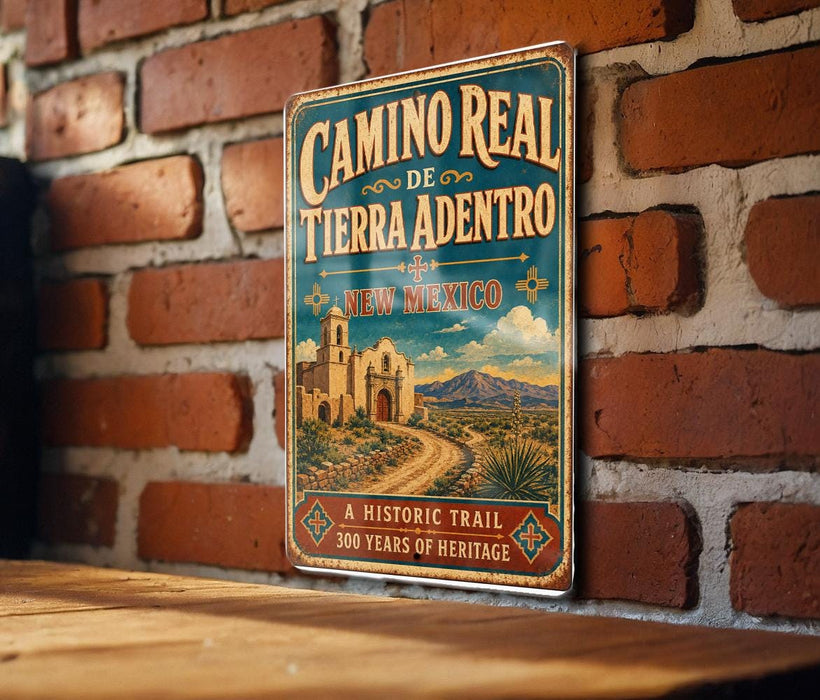 A vintage-style metal sign for the Camino Real, a historic trail in New Mexico, is displayed on a brick wall.