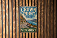 A vintage metal sign for the Crown Point Road in Vermont, featuring a scenic mountain landscape with a winding road and a lake.