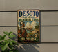 A vintage metal sign for the De Soto National Memorial Trail in Florida, featuring a historical illustration of a man in period attire and a ship in the background.