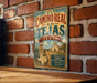 A vintage-style metal sign with the text "EL CAMINO REAL de los TEJAS TEXAS" is displayed on a brick wall.