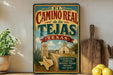A vintage-style sign for the Camino Real trail in Tejas, Texas, featuring a map of the region and a historical marker.