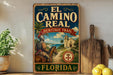 A vintage-style metal sign for the "El Camino Real Heritage Trail" in Florida, featuring a man on horseback and a scenic landscape.