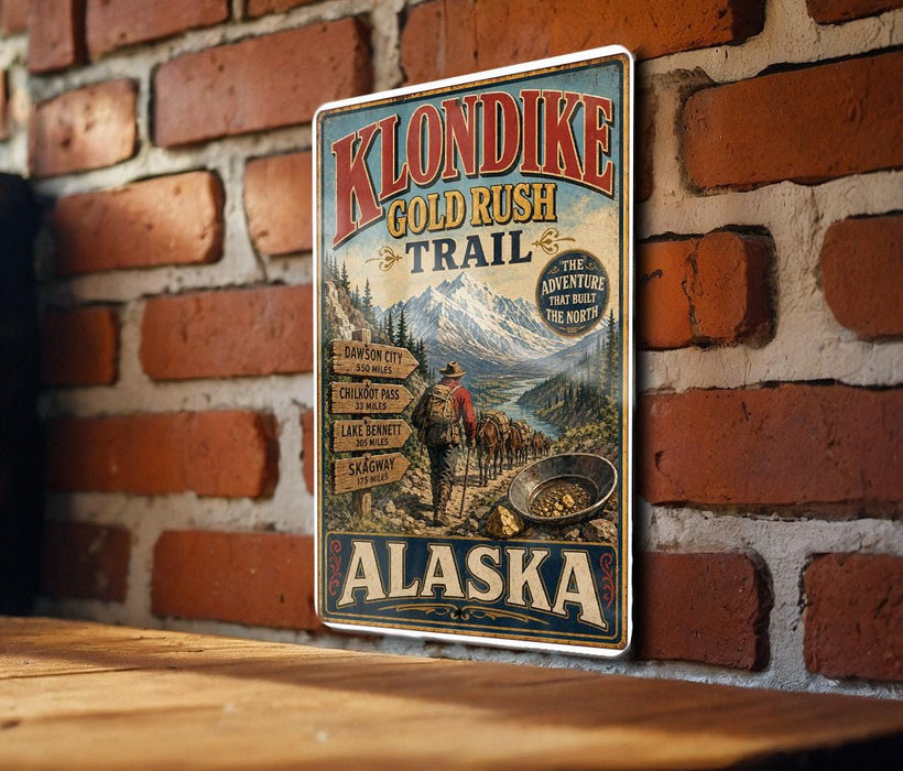 A vintage-style metal sign advertising Klondike Gold Rush Trail in Alaska, featuring a mountain landscape and a pan for gold.