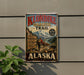 A vintage-style metal sign advertising Klondike Gold Rush Trail in Alaska, featuring a mountain landscape and a person hiking.