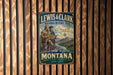 A vintage-style metal sign for the Lewis & Clark National Historic Trail in Montana, featuring two hikers on a mountain trail.