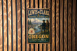 A vintage-style metal sign for the Lewis & Clark National Historic Trail in Oregon, featuring a scenic landscape with two figures in the foreground.