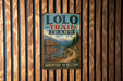 A vintage metal sign for the Lolo Trail in Idaho, featuring a scenic mountain landscape and trail information.