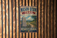 A vintage-style metal sign for the Mason-Dixon Trail in Pennsylvania, featuring a scenic illustration of a historic path and a stone marker.