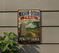 A vintage-style metal sign for the Mason-Dixon Trail in Pennsylvania, featuring a scenic illustration of a trail surrounded by lush greenery and a stone marker.