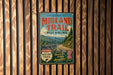 A vintage metal sign for the Midland Trail in West Virginia, featuring a scenic mountain landscape with a winding road and a bridge.