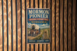 A vintage-style metal sign for the Mormon Pioneer National Historic Trail in Nebraska, featuring an illustration of a covered wagon and a sign with the words "Courage - Sacrifice - Hope".