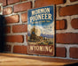A vintage-style sign for the Mormon Pioneer National Historic Trail in Wyoming, featuring an illustration of a covered wagon and mountains in the background.