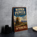 A vintage-style sign for the Mormon Pioneer National Historic Trail in Wyoming, featuring an illustration of a covered wagon and mountains in the background.
