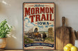 A vintage-style metal sign for the historic Mormon Trail in Iowa, featuring an illustration of a wagon train traveling through the state.