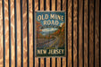 a vintage-style sign for the Old Mine Road in New Jersey, mounted on a wooden wall.