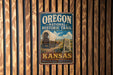 A vintage-style metal sign for the Oregon National Historic Trail in Kansas, featuring a wagon and a sign with the text "OREGON NATIONAL HISTORIC TRAIL KANSAS Discover the Legacy - Honor the Journey".