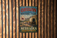 A vintage-style metal sign for the Oregon National Historic Trail in Nebraska, featuring an illustration of a covered wagon traveling along the Oregon Trail.