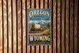 A vintage-style sign for the Oregon National Historic Trail in Wyoming, featuring a wagon on a trail surrounded by mountains.