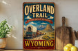 a vintage-style sign for the "Overland Trail" in Wyoming, with a wagon train depicted on the sign. The sign is displayed on a shelf next to a wooden cutting board and a potted plant.