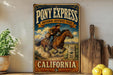 A vintage-style sign for Pony Express National Historic Trail in California, featuring a cowboy riding a horse.