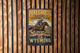 A vintage-style metal sign for Pony Express National Historic Trail, featuring a cowboy riding a horse, mounted on a wooden wall.