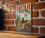 A vintage-style metal sign for the Santa Fe National Historic Trail in Kansas, featuring an illustration of a wagon train and a monument.