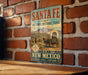 A vintage-style metal sign for the Santa Fe National Historic Trail in New Mexico, featuring an illustration of a covered wagon and a cowboy on horseback.