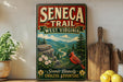 a vintage-style sign for the Seneca Trail in West Virginia, with a scenic mountain landscape and a red cardinal bird. The sign is displayed on a shelf, surrounded by various kitchen items such as a cutting board, a lemon, and a potted plant.