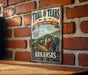 A vintage-style sign for the Trail of Tears, a historic trail in Arkansas, is displayed on a brick wall.